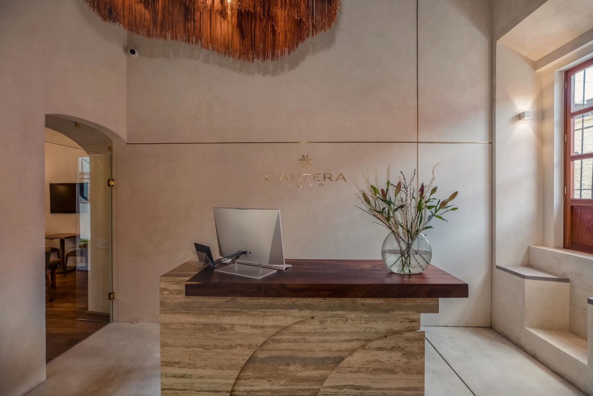 hay un escritorio con una computadora y un jarrón de flores