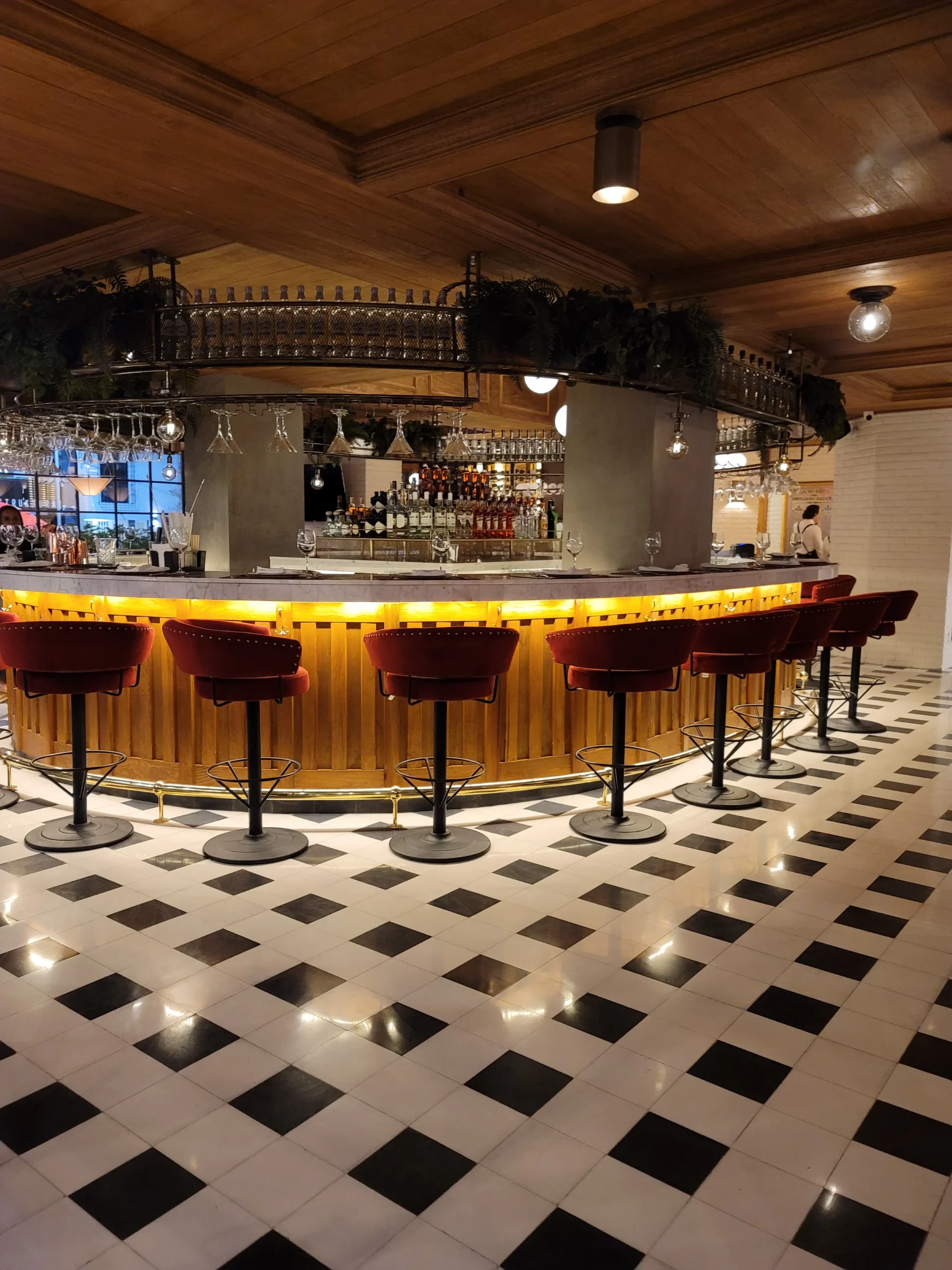 bar arafed con sillas rojas y un piso a cuadros blanco y negro