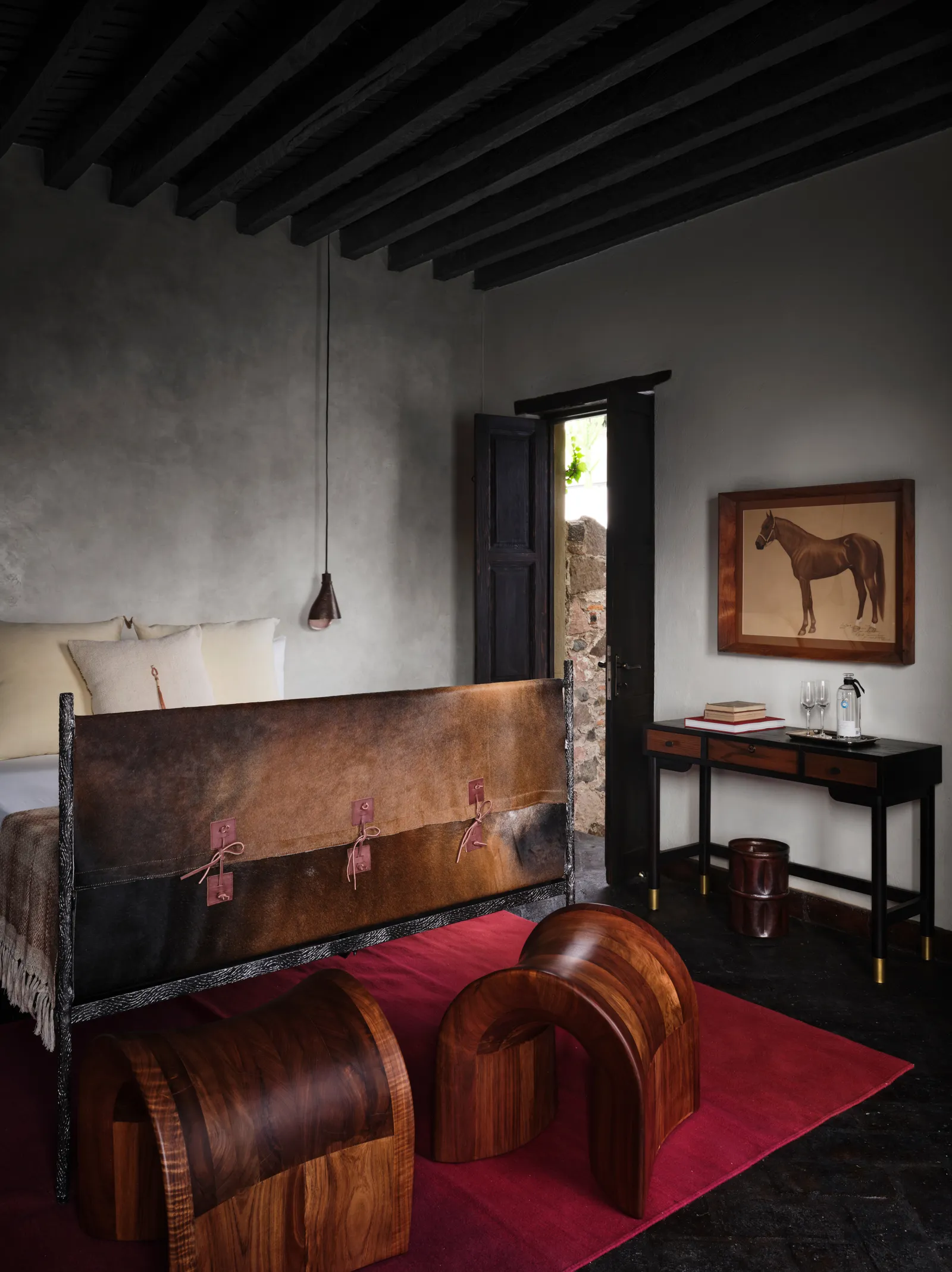 una cama con cabecera de madera y taburetes de pies