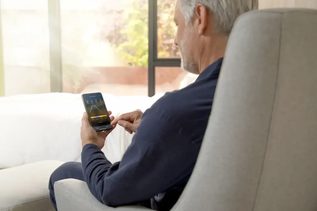 un hombre sentado en un sofá usando su teléfono celular