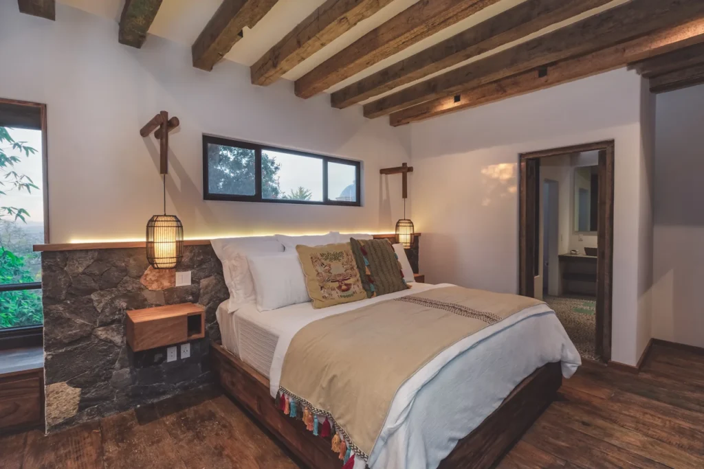 Una habitación con una gran cama y lámparas colgantes con iluminación indirecta