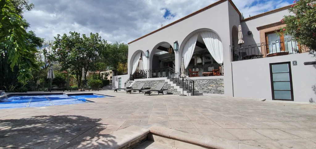 Una entrada principal de una lujosa casa con piscina y cortinas automatizadas