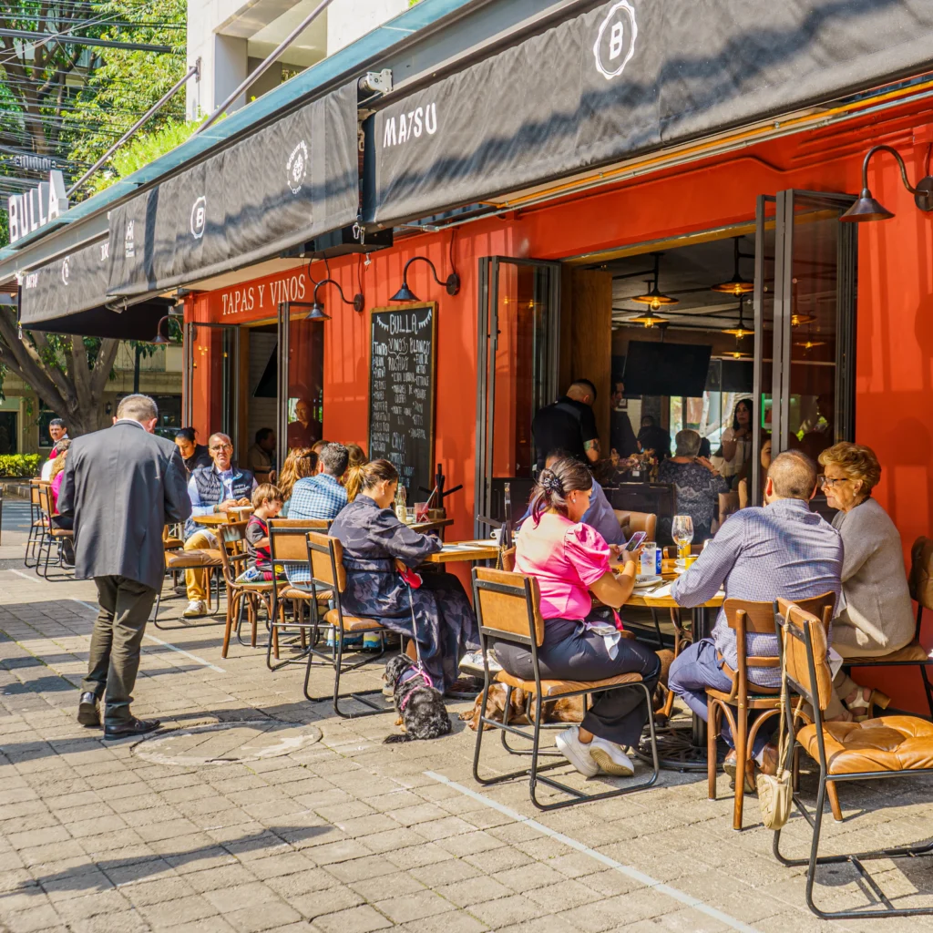 Un restaurante desde la parte exterior con personas sentadas en las mesas externas