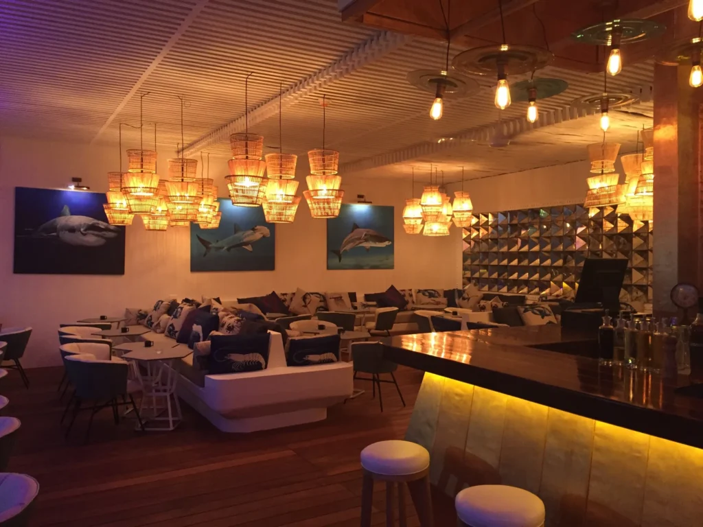 Un restaurant con asientos blancos e iluminación colgada en el techo